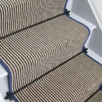 Hardy striped wool stair runner with blue edging and black stair rods.