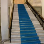 Long marble staircase with a bright blue carpet runner