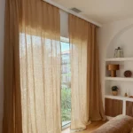 Natural beige linen curtains hanging over a full-length window