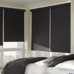 Two black blackout roller blinds covering windows