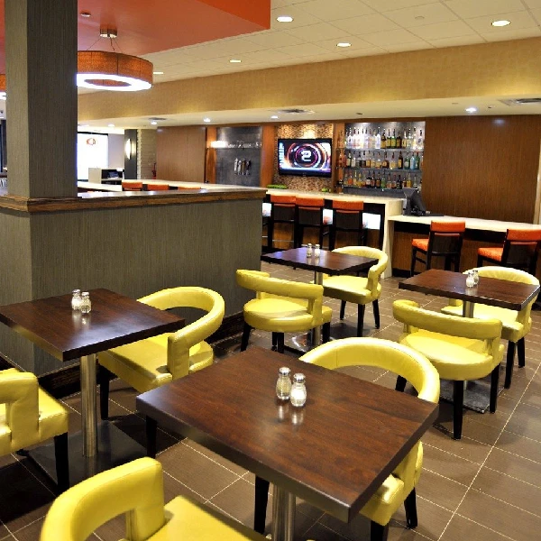 dark wood tables and bright yellow custom tub-style dining chairs, in restaurant
