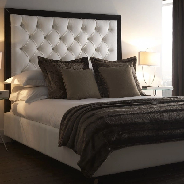 white button-tufted headboard framed by dark wood fabric