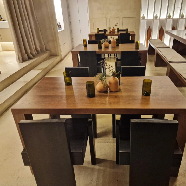 wooden dining tables with dark wood bases are set with black chairs