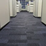 Blue-gray striped commercial carpet tiles in office corridor