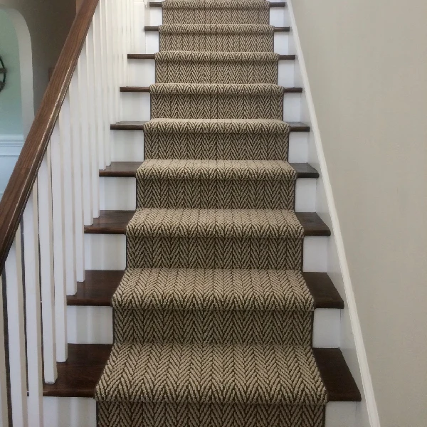 Dark brown and beige chevron-patterned carpet runner on dark wood stairs