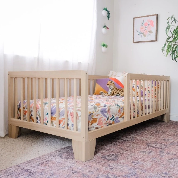 Light wood toddler bed with slatted sides and decorative legs