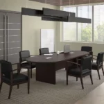 Oval dark wood conference table surrounded by black leather office chairs