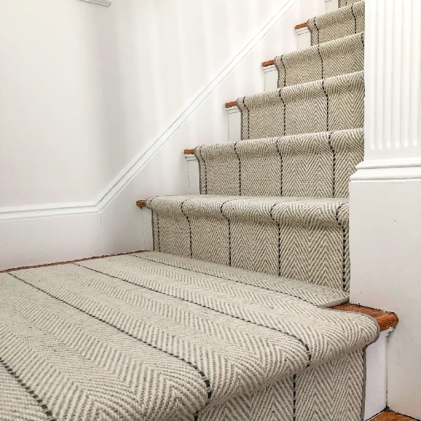 Striped carpet runner with a chevron weave on a wooden staircase.