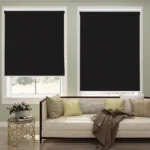 Two black blackout roller blinds partially covering windows