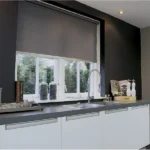 gray roller blind partially covering a white-framed kitchen window