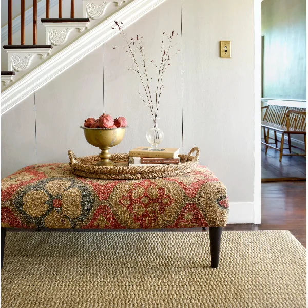 natural woven sisal carpet visible beneath a patterned ottoman